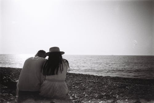 Man and Woman Sitting on Beach Shore