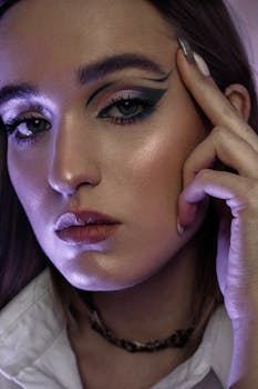 Close-up portrait of a woman with bold eye makeup and subtle lighting, highlighting her beauty.