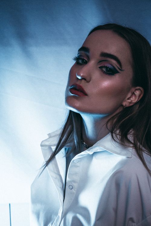 Free Portrait of a woman with bold eye makeup and lighting effects, conveying elegance and style. Stock Photo