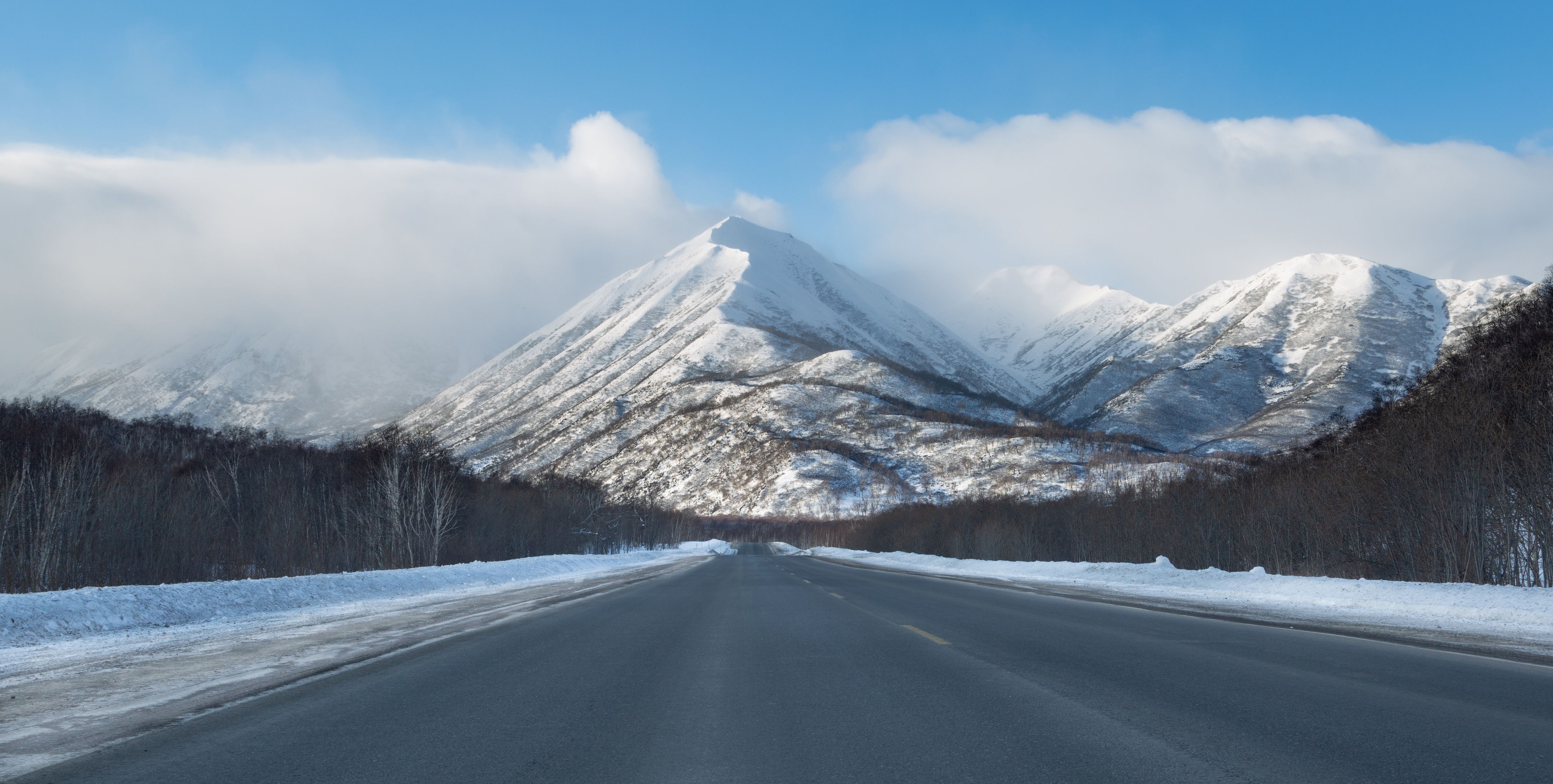 A cleared road running straight towards a snow-covered ridge