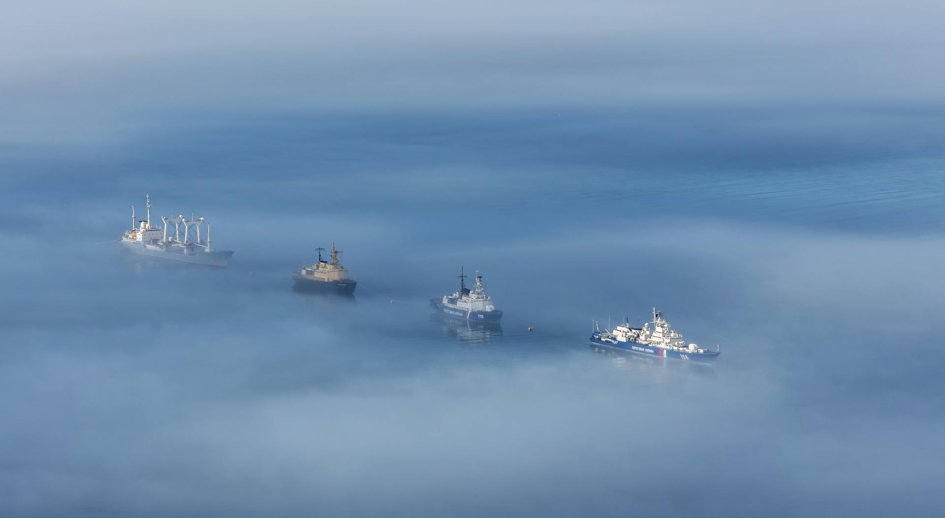 Aerial view of ships floating serenely in a foggy ocean, creating a tranquil maritime scene.