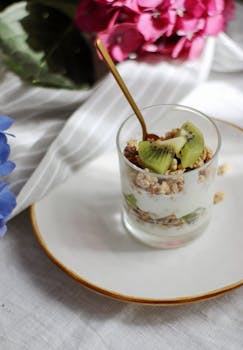 Delicious kiwi yogurt parfait with crunchy granola, garnished elegantly on a white plate.