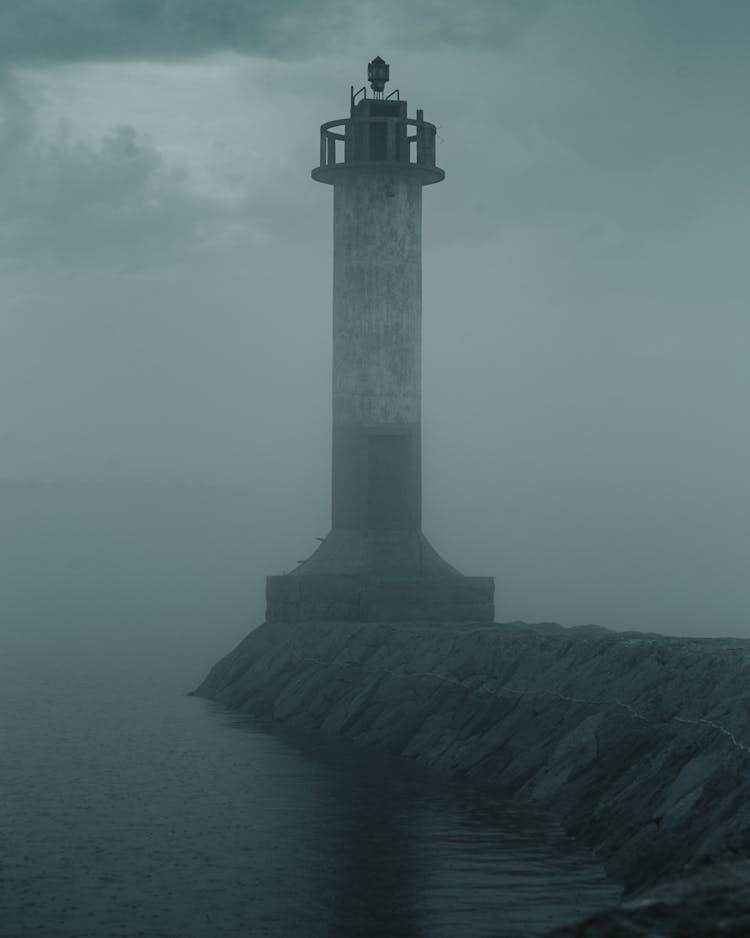 A Lighthouse On A Concrete Dock Beside The Sea