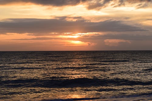 A Beach Waves Crashing on Shore During Sunset