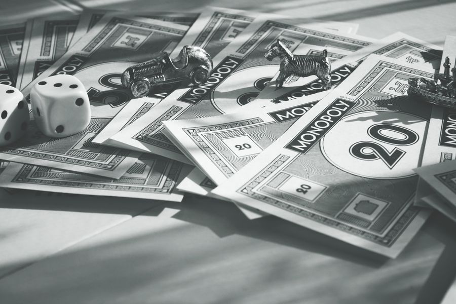 A close-up of monopoly money, dice, and game pieces in monochrome color scheme.
