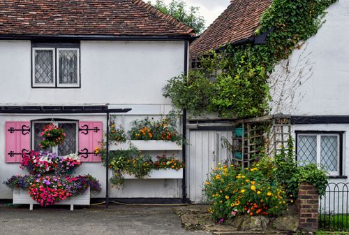 Free Picturesque English cottage facade adorned with colorful flowers and lush greenery in Eynsford. Stock Photo