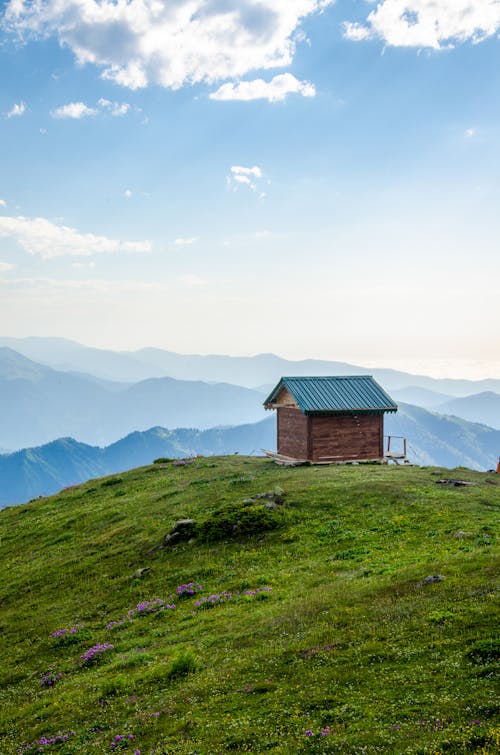 A Wooden House on Grass Field Under the Blue Sky