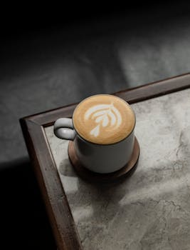 A close-up of a latte with intricate art design on a marble table, perfect for coffee lovers and cafes.