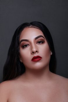 Stunning portrait of a woman with makeup and red lipstick on a gray background.