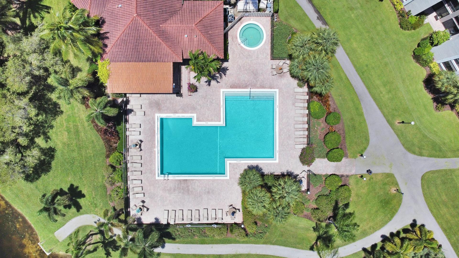 Aerial shot of a beautifully landscaped backyard featuring a swimming pool and lush greenery.