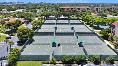 Free Aerial shot of tennis courts surrounded by trees and buildings in a sunny urban setting. Stock Photo