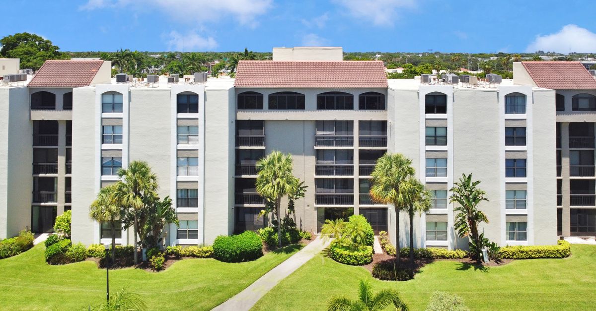 Elegant apartment building surrounded by green lawns and palm trees, perfect for urban living.