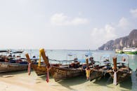 沙滩上停泊的长尾船风景优美，海水清澈，悬崖遥远