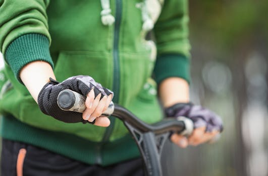 A person wearing gloves rides a scooter, focusing on the handle bars.
