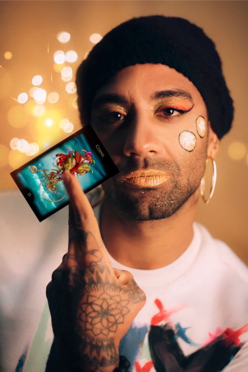 Free Creative studio portrait of a man with makeup and tattoos, holding a tarot card. Stock Photo