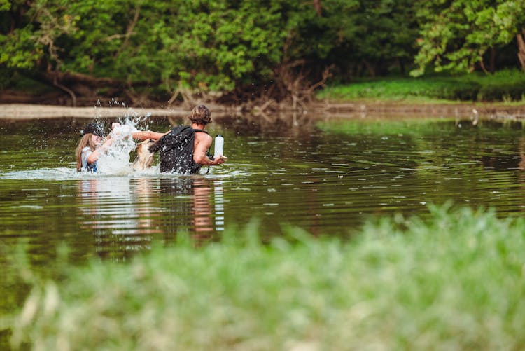 Couple Playing On Water With Dog