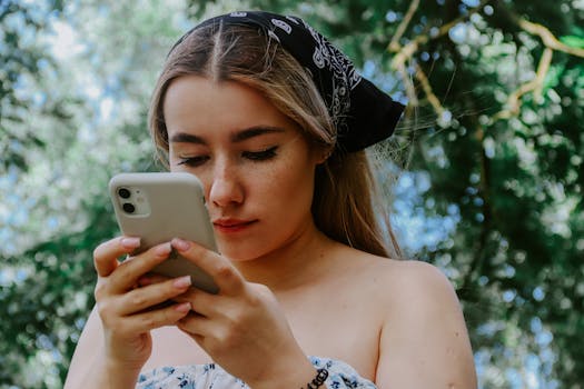 Woman with a bandana focusing on her smartphone in a lush outdoor setting