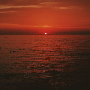 A vivid sunset over the ocean with warm colors and serene waters framed by a dramatic orange sky.