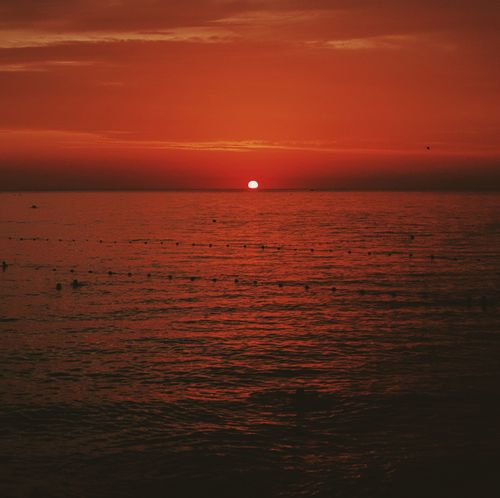 Free A vivid sunset over the ocean with warm colors and serene waters framed by a dramatic orange sky. Stock Photo