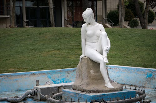 Голая женщина белая бетонная статуя возле зеленой травы
