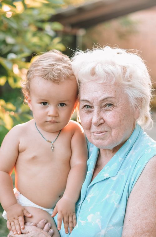 Free Charming portrait of a grandmother with her grandchild in a sunny garden setting. Stock Photo