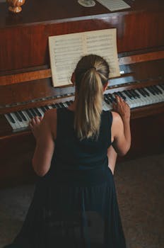A woman playing the piano with sheet music in a warm interior setting.