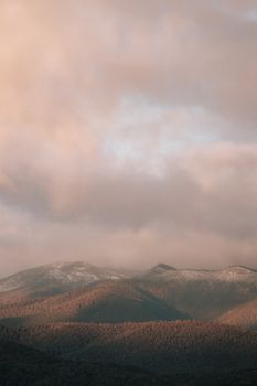 A serene mountain landscape in Canberra bathed in morning light with clouds creating a moody atmosphere.