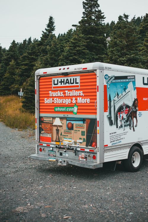 Free A U-Haul truck parked on a gravel road amidst lush greenery, showcasing the brand's design. Stock Photo