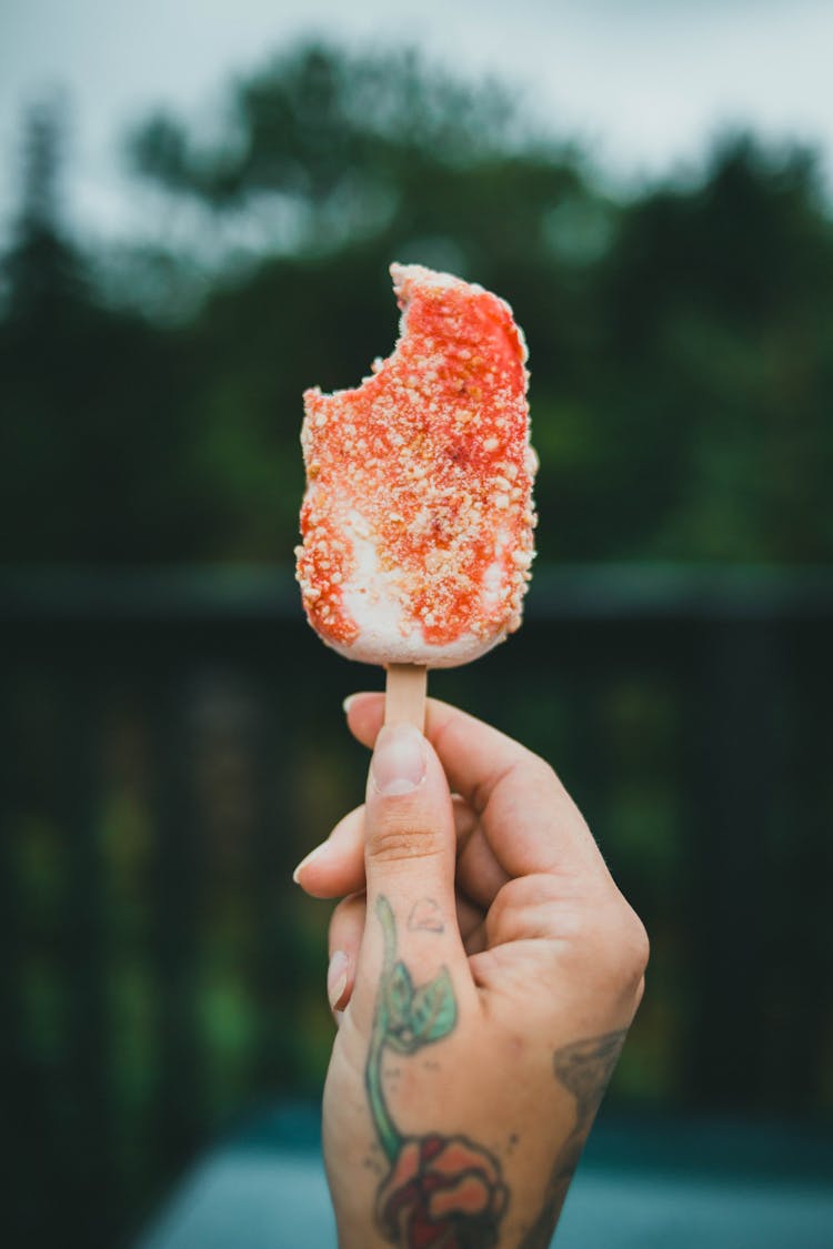 A Person Holding An Ice Cream On A Popsicle Stick