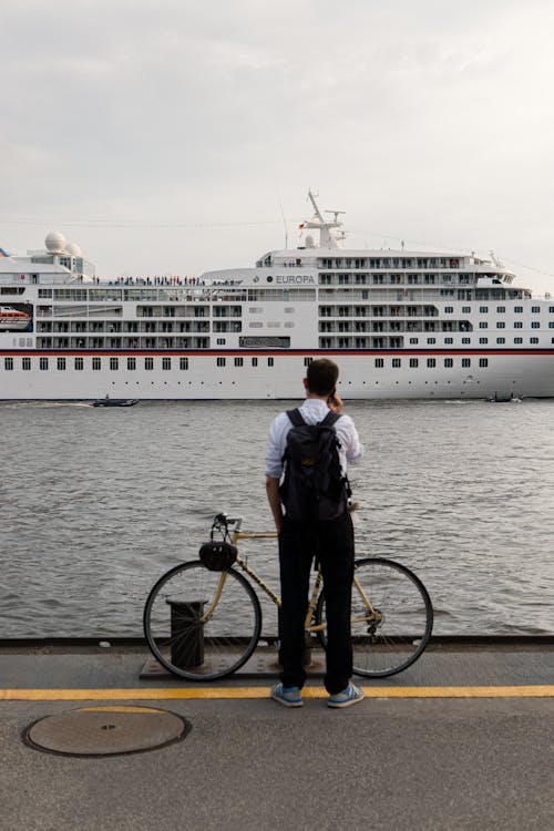Man Talking on Phone In Front of a Ship on Water 