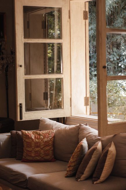 Inviting living room featuring a comfortable sofa with throw pillows and open windows, creating a warm ambiance.