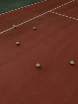Multiple tennis balls on a clay tennis court highlighting game practice setup.