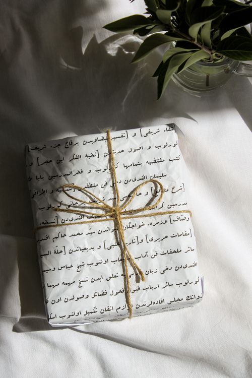 Free Close-up of a gift wrapped in Arabic script paper with twine, elegant handmade style. Stock Photo