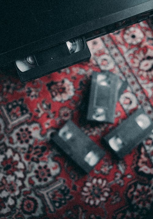 From above of collection of similar vintage cassettes in video recorder and on colorful retro carpet
