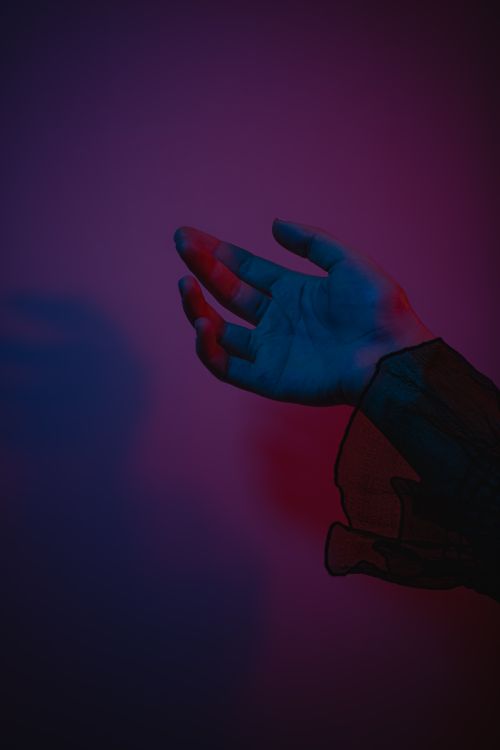 Free Close-up of a hand illuminated by vibrant colored lights creating a dramatic mood. Stock Photo