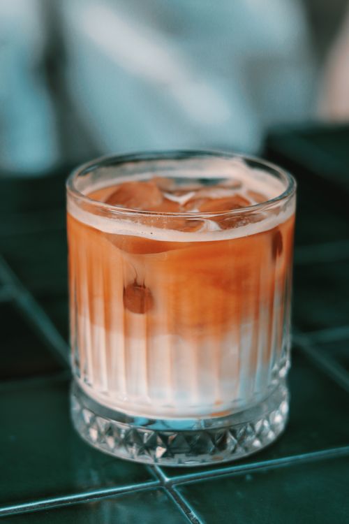 Free Close-up of a clear glass with iced coffee and milk on a dark table surface. Stock Photo