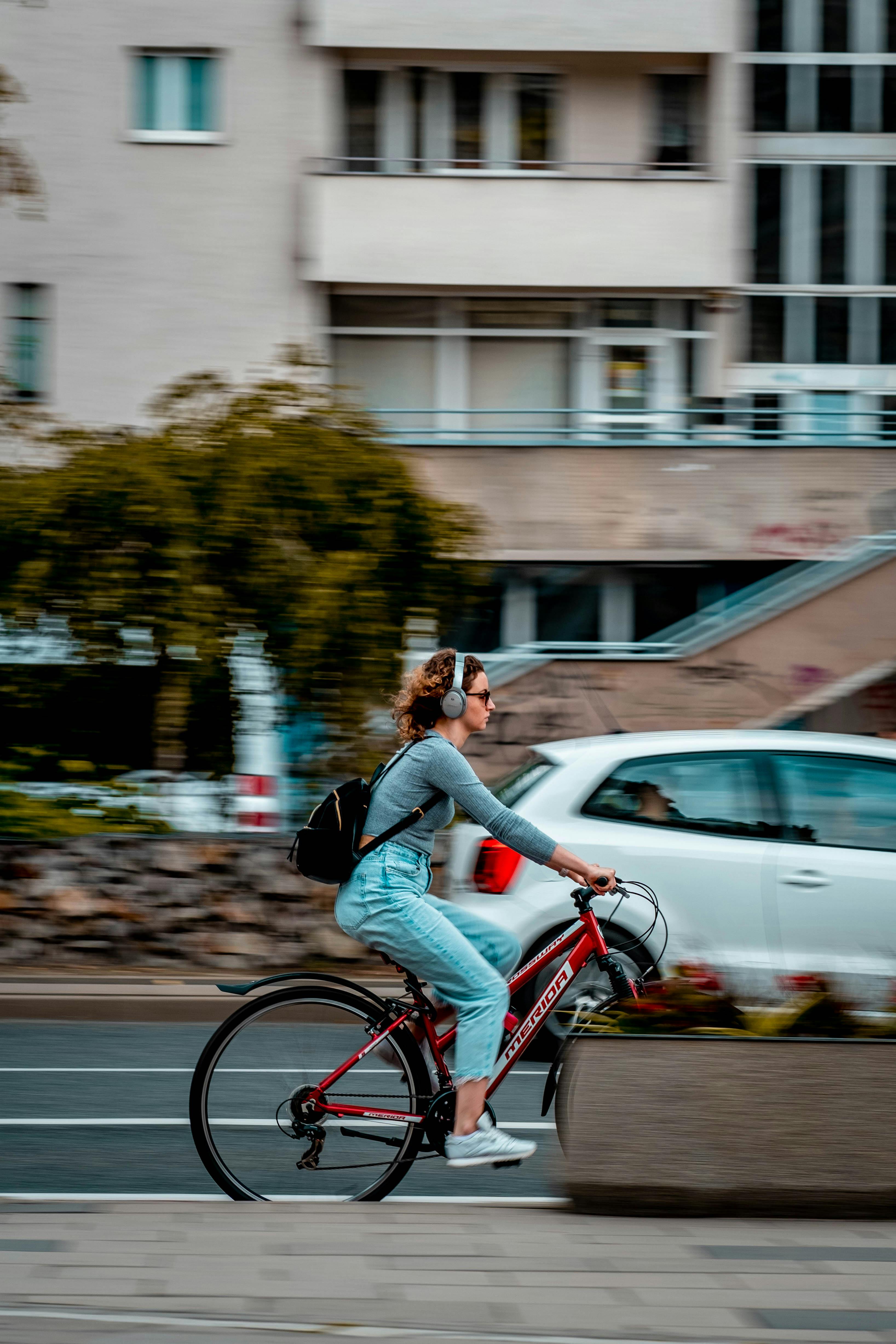 Woman Wearing Headset Riding a Bike on the Road · Free Stock Photo