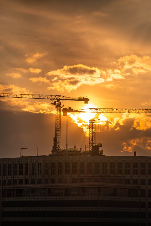 Silhouette of Construction Cranes During Sunset