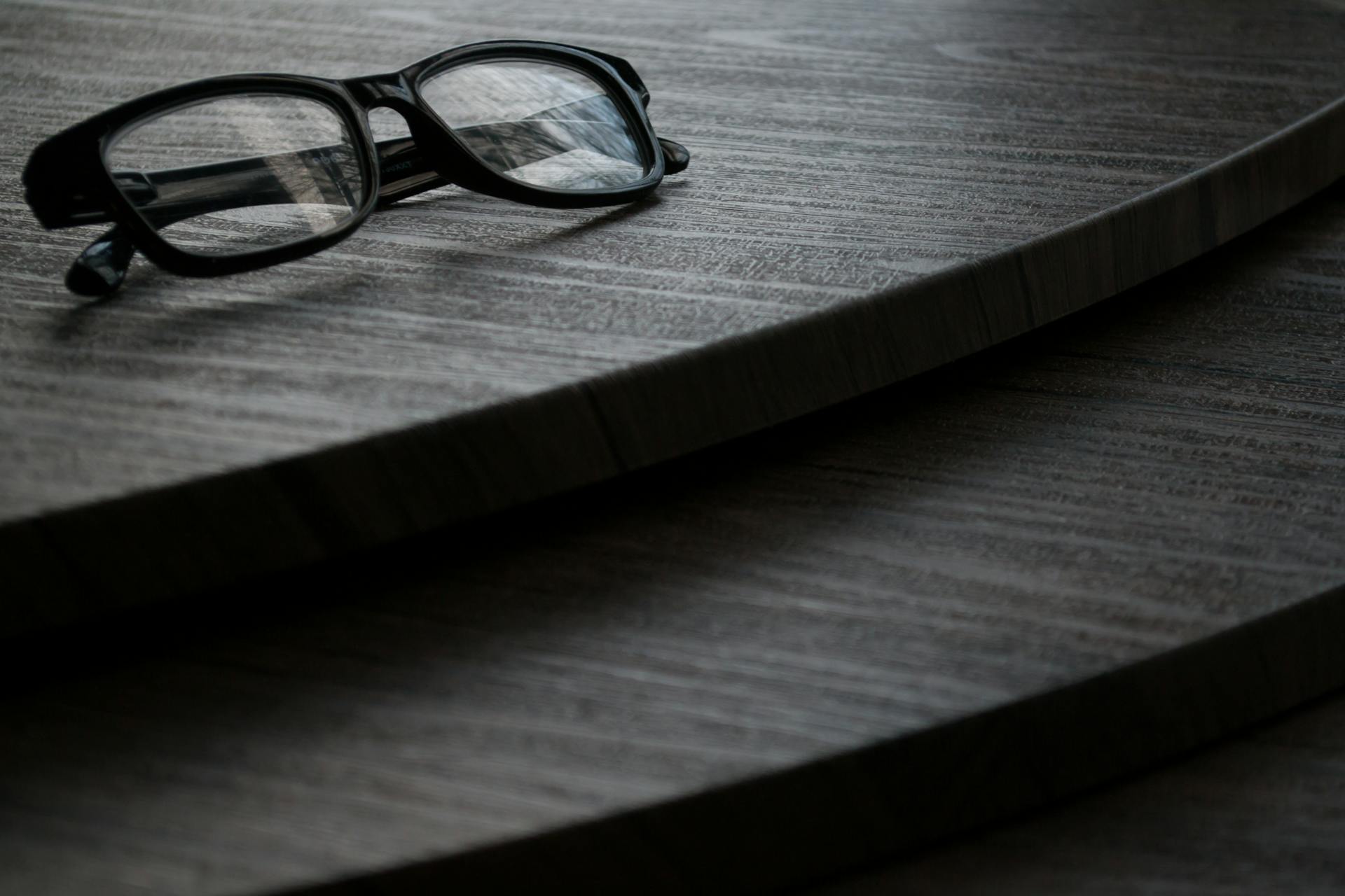 A close-up of vintage eyeglasses resting on a wooden surface, showcasing classic design.