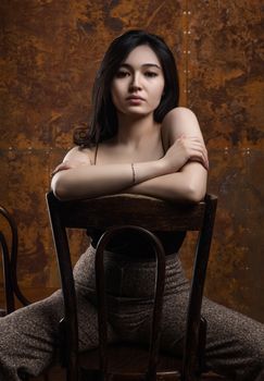 A stylish portrait of a young woman posing with a chair in a studio setting.