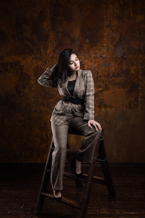 Woman in Plaid Blazer and Pants Sitting on Ladder