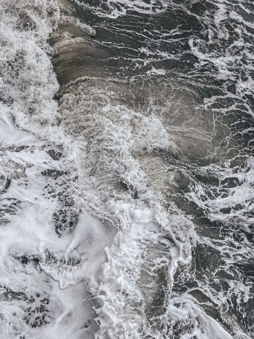 Free Aerial view capturing the power and movement of ocean waves crashing against the shore. Stock Photo
