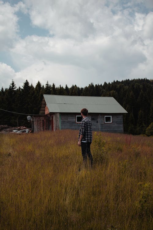 AS Man Standing on the Grass Field Under a Cloudy Sky