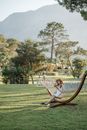Woman in Black Shirt Sitting on Brown Wooden Bench on Green Grass Field