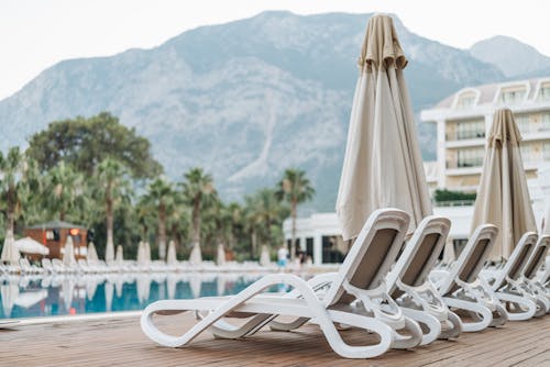 Free Sun Loungers Near a Beach Umbrella on a Wooden Deck Stock Photo