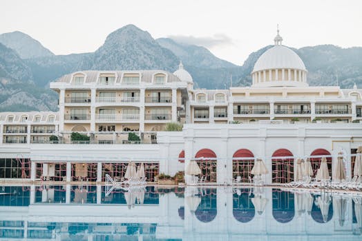 Elegant resort facade with pool, surrounded by mountains, perfect for a luxurious vacation getaway.