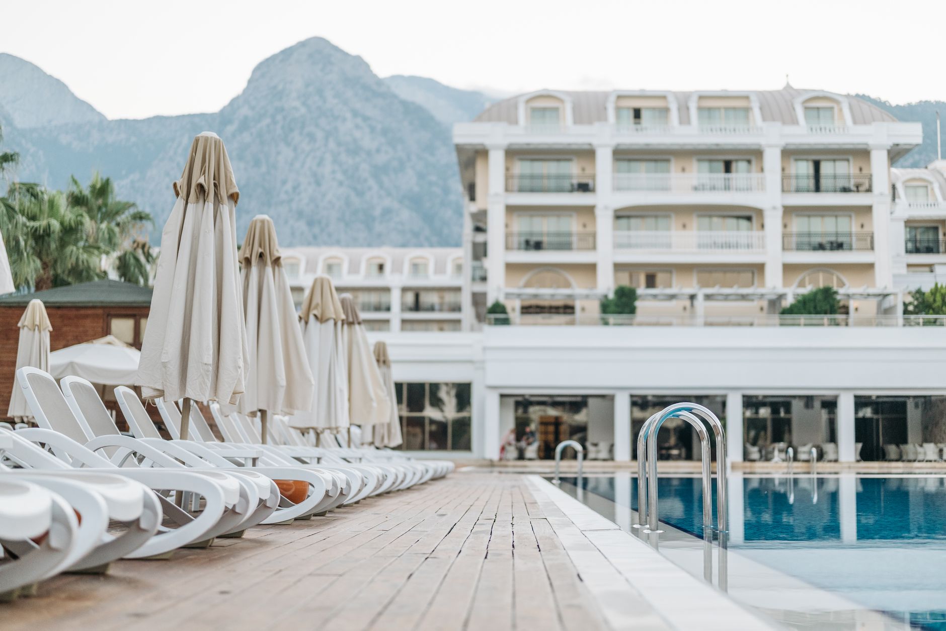 Sun loungers and umbrellas by a luxury resort pool for a calm last-day departure
