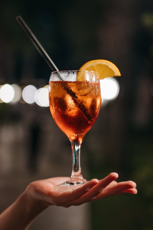 Person Holding Clear Wine Glass With Cocktail and Sliced Orange