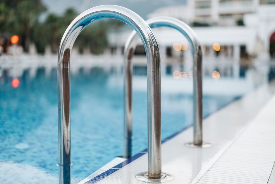 Close-up of a pool ladder at a serene resort, evoking summer vacation vibes.