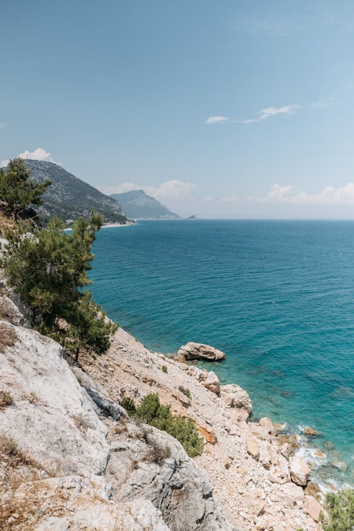 Blue Sea Near Rocky Shore Under a Blue Sky